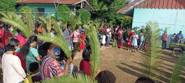 Umat Katolik mengikuti perayaan misa singkat di halaman SD YPPK Buti sambal memegang daun palma – Surya Papua/Frans Kobun