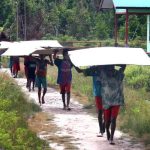 Masyarakat bergotong royong menjinjing tripleks dari pelabuhan ke lokasi pembangunan perumahan – Surya Papua/IST