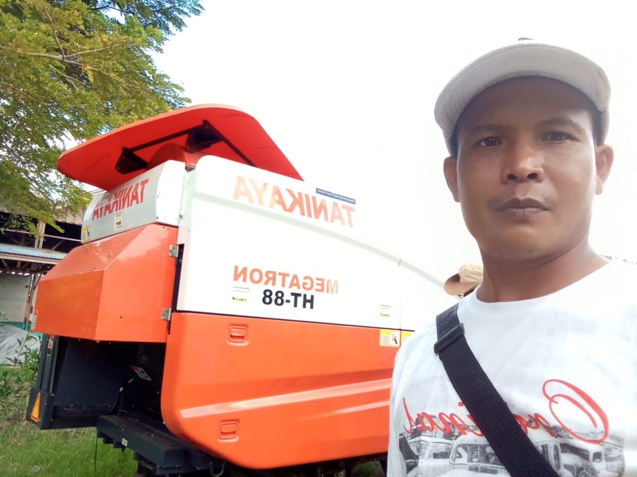 Ketua Gapoktan Kampung Sumber Mulya, Arif Wijaya foto dengan latar harvester combine – Surya Papua/IST