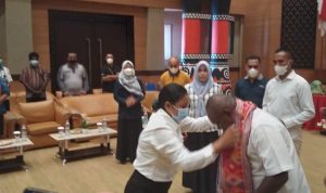 Salah seorang CPNS sedang mengenakan selendang NTT kepada Bupati Merauke, Romanus Mbaraka – Surya Papua/Yulianus Bwariat