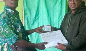 Operator Pencetakan e-KTP Disdukcapil Kabupaten Merauke, Alex Rumabatu sedang menyerahkan kartu keluarga serta e-KTP- Surya Papua/IST