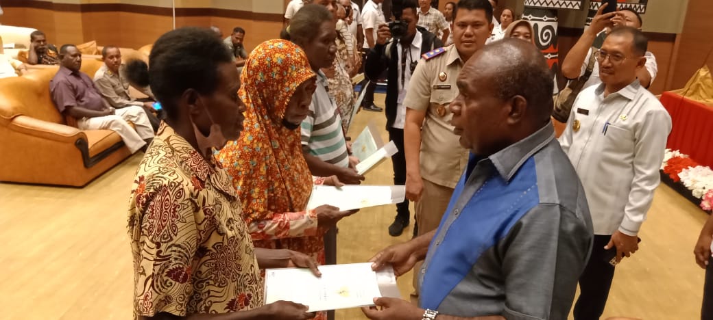 Bupati Merauke, Romanus Mbaraka sedang menyerahkan sertifikat tanah kepada masyarakat – Surya Papua/Yulianus Bwariat