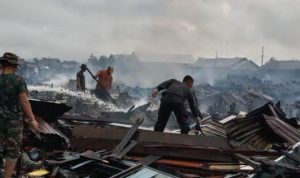 TNI sedang bersama masyarakat melakukan pembersihan puing-puing kebakaran ratusan rumah dan kios – Surya Papua/Yulianus Bwariat