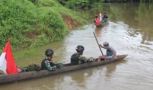 Prajurit Satgas-Pamtas sedang menggunakan perahu lesung menyeberang sungai Kombut untuk melakukan pemantauan patok perbatasan RI-PNG – Surya Papua/IST