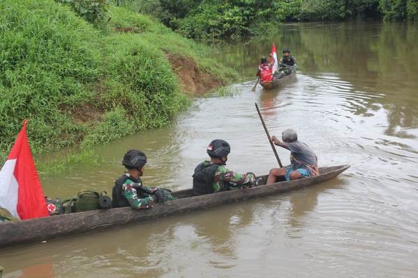 Prajurit Satgas-Pamtas sedang menggunakan perahu lesung menyeberang sungai Kombut untuk melakukan pemantauan patok perbatasan RI-PNG – Surya Papua/IST