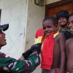 Prajurit Satgas Pamtas sedang mengenapakan pakaian kepada salah seorang anak – Surya Papua/IST