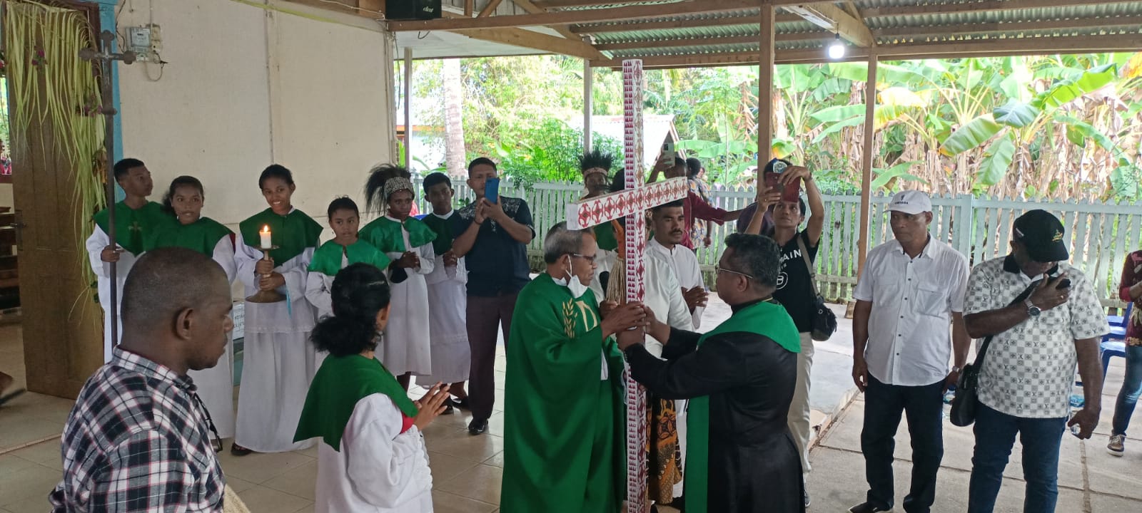 Pastor Paroki Santa Theresia Buti, Pius Oematan, Pr sedang menerima Salib IYD dari Pastor Sony Walewawan, Pr – Surya Papua/Frans Kobun