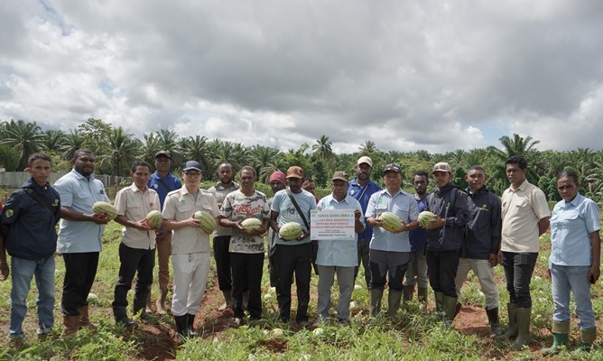 Pihak perusahan bersama masyarakat foto bersama sambil menunjuk semangka yang dipanen – Surya Papua/IST