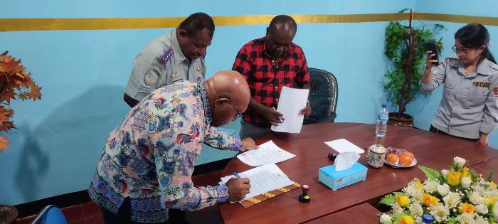 Pastor John Kandam, Pr sedang menandatangani berita acara penyerahan bus – Surya Papua/Frans Kobun