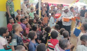 Bupati Merauke, Romanus Mbaraka sedang membagikan kue kepada anak-anak di Kampung Kaliki – Surya Papua/Frans Kobun