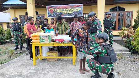 Salah seorang anggota Satgas Yonif 125 SMB sedang mengenakan pakaian kepada salah satu anak – Surya Papua/IST