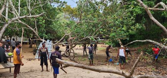 Masyarakat sedang bergotong royong memotong dahan kayu dan pohon di sekitar Pantai Pulau Habe – Surya Papua/IST