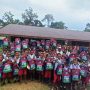 Ratusan anak di SD Kweel, Distrik Elikobel sedang foto bersama dengan Bupati Merauke, Romanus Mbaraka sambil mengangkat tas sekolah serta botol air minum- Surya Papua/Frans Kobun