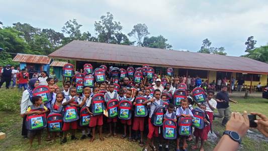 Ratusan anak di SD Kweel, Distrik Elikobel sedang foto bersama dengan Bupati Merauke, Romanus Mbaraka sambil mengangkat tas sekolah serta botol air minum- Surya Papua/Frans Kobun