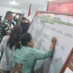 Ketua KPU Kabupaten Merauke, Rosiana Kebubun sedang menandatangani spanduk saat deklarasi pemilu damai di Kodim 1707 Merauke – Surya Papua/Frans Kobun