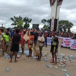 Sejumlah mama papua yang menghamburna botol-botol vit di aspal saat aksi demonstrasi – Surya Papua/Frans Kobun