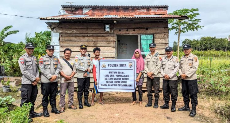 Kapolsek Sota, Ipda Yustus Maudul bersama anggotanya foto bersama Waris, warga Kampung Sota setelah pemasangan meteran listrik di rumahnya – Surya Papua/IST