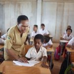 Seorang guru sekolah dasar di Papua dengan penuh kesabaran sedang mengajar murid-muridnya – Surya Papua/IST