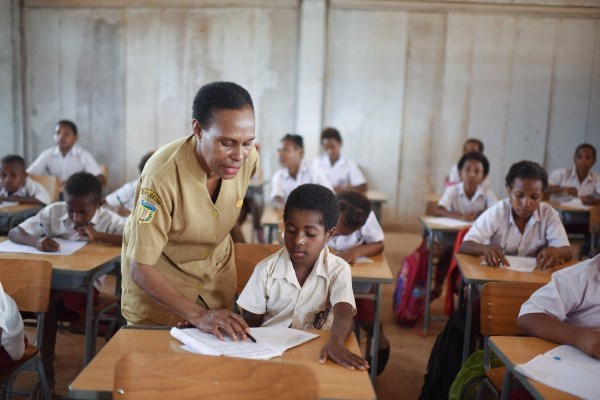 Seorang guru sekolah dasar di Papua dengan penuh kesabaran sedang mengajar murid-muridnya – Surya Papua/IST