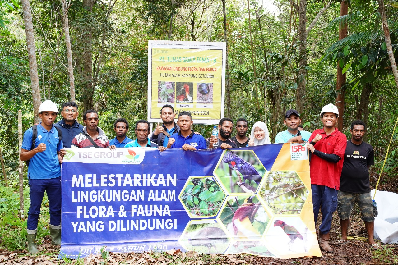 Foto bersama masyarakat serta karyawan usai pemasangan tulisan di sehelai kain – Surya Papua/IST