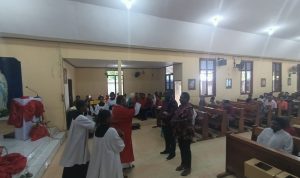 Pastor Simon Petrus Matruty sedang memerciki air berkat kepada dua orang yang resmi masuk atau bergabung Gereja Katolik – Surya Papua/Frans Kobun