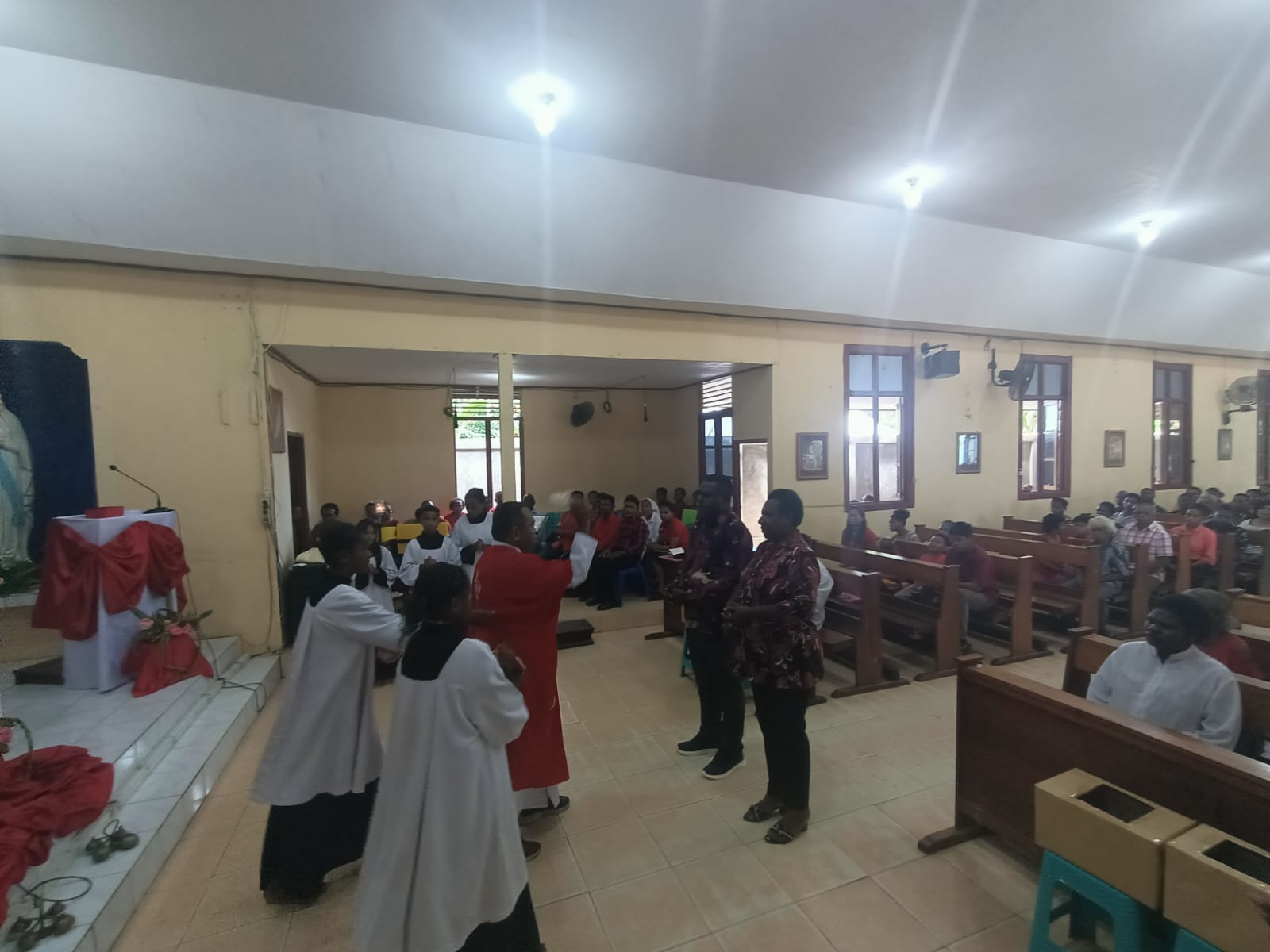 Pastor Simon Petrus Matruty sedang memerciki air berkat kepada dua orang yang resmi masuk atau bergabung Gereja Katolik – Surya Papua/Frans Kobun