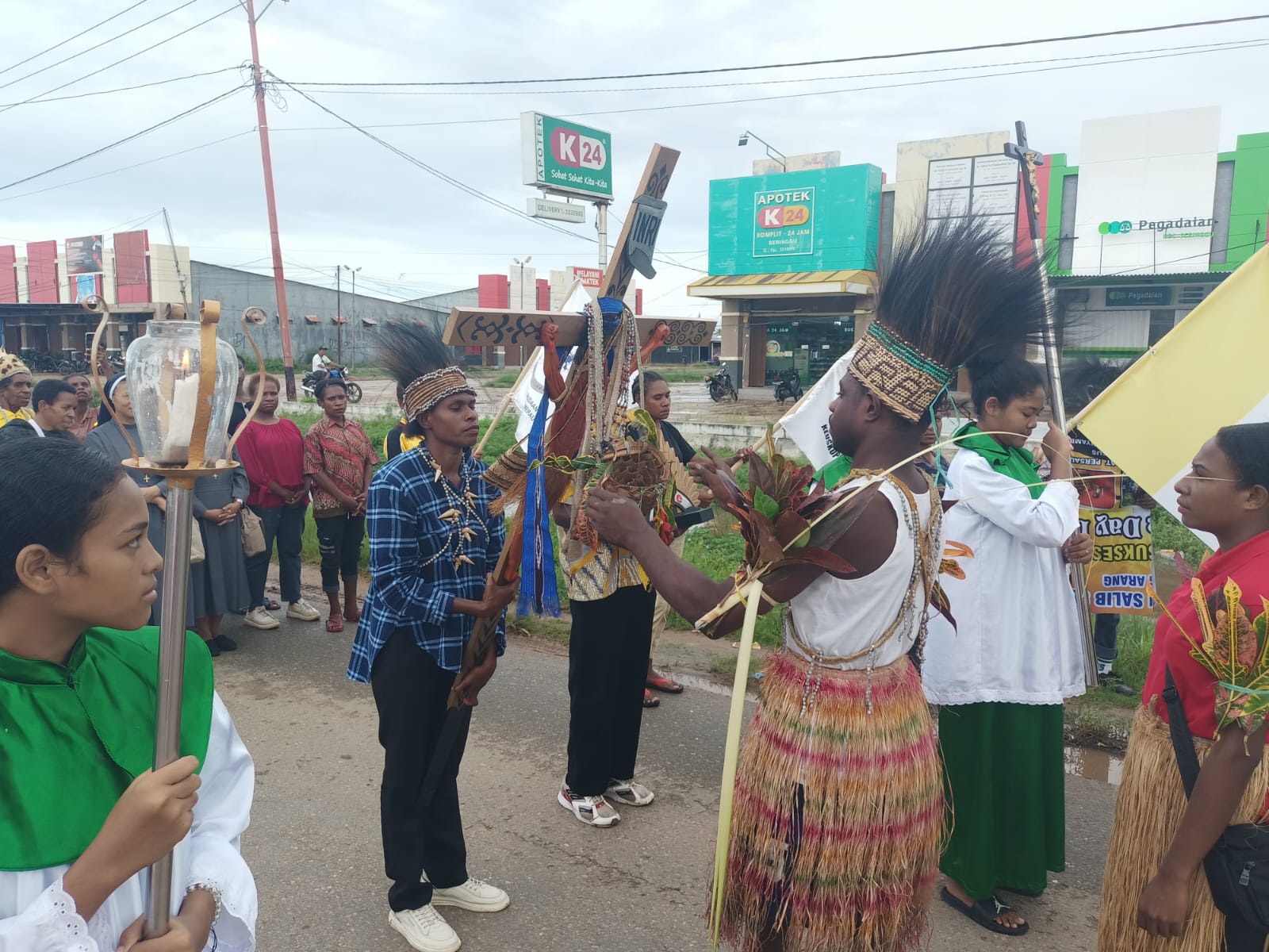 Atribut adat dikenakan ke Salib PYD oleh perwakilan umat paroki Santa Theresia Buti – Surya Papua/Frans Kobun