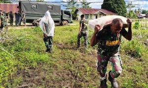 Salah seorang prajurit TNI sedang memikul semen setelah diturunkan dari truk – Surya Papua/IST