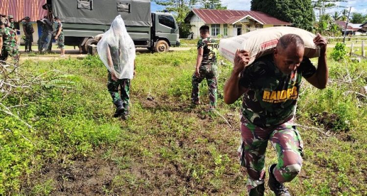 Salah seorang prajurit TNI sedang memikul semen setelah diturunkan dari truk – Surya Papua/IST
