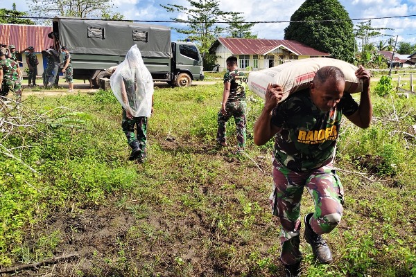 Salah seorang prajurit TNI sedang memikul semen setelah diturunkan dari truk – Surya Papua/IST