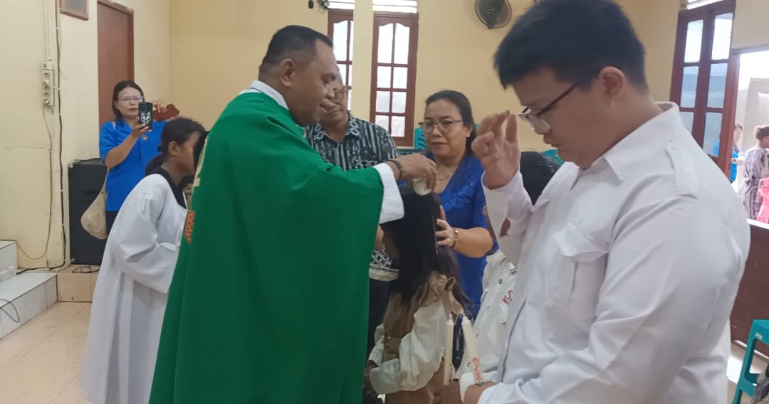 Ketiga putra-putri dari Yuliana sedang dibaptis oleh Pastor Simon Petrus Matruty – Surya Papua/Frans Kobun