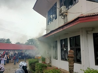 Asap keluar dari dalam Kantor Telkom saat aksi massa yang berlangsung tadi pagi – Surya Papua/Frans Kobun