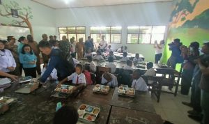 Anak-anak di SD Gudang Arang Merauke sedang menikmati makan bergizi gratis (MBG) – Surya Papua/Frans Kobun