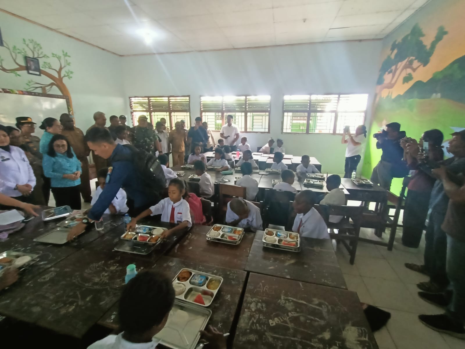 Anak-anak di SD Gudang Arang Merauke sedang menikmati makan bergizi gratis (MBG) – Surya Papua/Frans Kobun