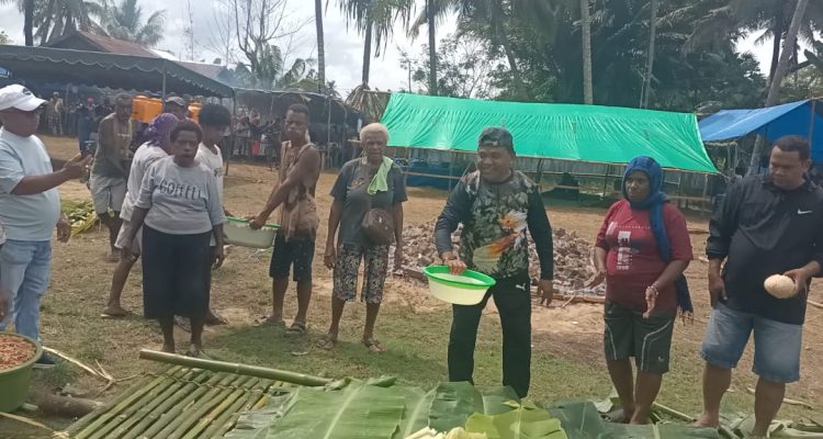 Pastor Paroki Santa Theresia Buti, Simon Petrus Matruty sedang memegang sagu sep yang siap dibakar-Surya Papua/Frans Kobun
