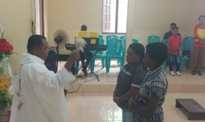 Pastor Simon Petrus Matruty sedang memerciki Nathalia dengan air berkat – Surya Papua/Frans Kobun