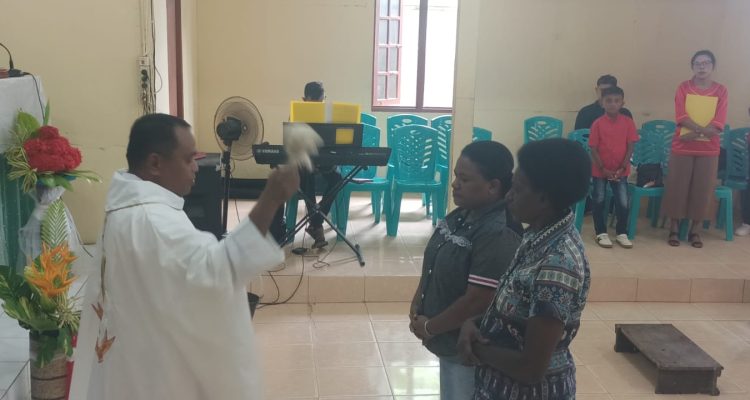 Pastor Simon Petrus Matruty sedang memerciki Nathalia dengan air berkat – Surya Papua/Frans Kobun