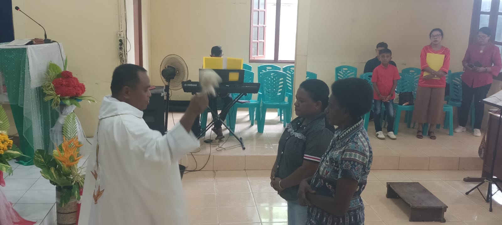 Pastor Simon Petrus Matruty sedang memerciki Nathalia dengan air berkat – Surya Papua/Frans Kobun