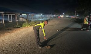 Salah seorang anggota polisi sedang menunjuk lokasi atau tempat korban ditabrak – Surya Papua/IST