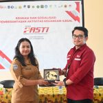 Pemberian plakat dalam sosialisasi yang dilakukan OJK di Kelurahan Muli – Surya Papua/IST