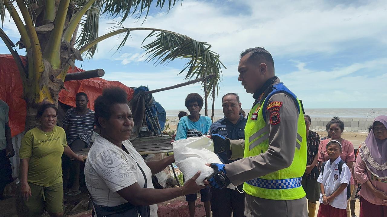 Kapolres Merauke, Leonardo Yoga sedang menyerahkan bantuan beras kepada warga yang terdampak banjir rob – Surya Papua/IST