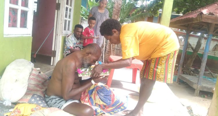 Salah seorang bapak sedang mencium Kanak-Kanak Yesus saat diarak di rumahnya – Surya Papua/IST