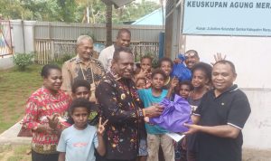 Bupati Merauke, Yoseph Bladib Gebze menyerahkan secara simbolis bantuan kepada Pastor Paroki Santa Theresia Buti, Simon Petrus Matruty – Surya Papua/Frans Kobun