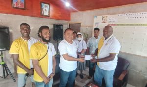 buti 3 Penyerahan bantuan dana oleh Ketua Pemuda Buti Bangkit, Leonardus Ndiken kepada Pastor Simon Petrus Matruty – Surya Papua/Frans Kobun