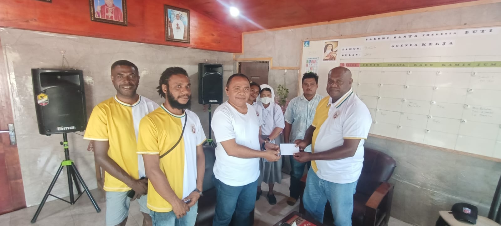 Penyerahan bantuan dana oleh Ketua Pemuda Buti Bangkit, Leonardus Ndiken kepada Pastor Simon Petrus Matruty – Surya Papua/Frans Kobun