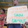 Seorang anak di Kampung Kiworo, Distrik Kimaam sedang memegang sehelai kertas dengan tulisan penolakan PSN saat aksi di Lapangan Maskura-Kimaam – Surya Papua/Frans Kobun