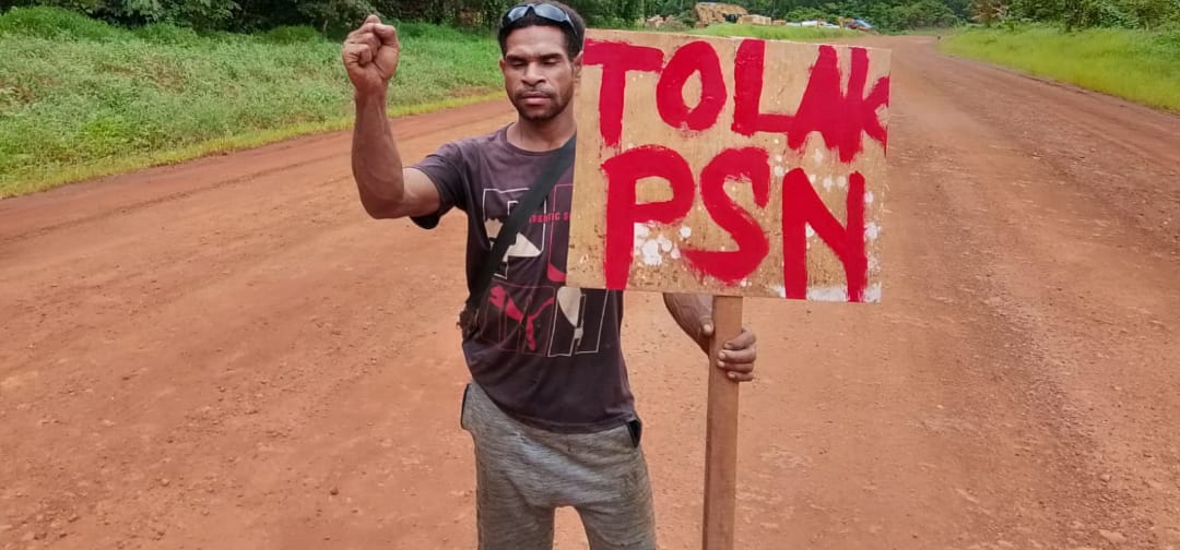Sebuah tulisan penolakan PSN yang ditunjukkan seorang pemuda Marind – Surya Papua/IST