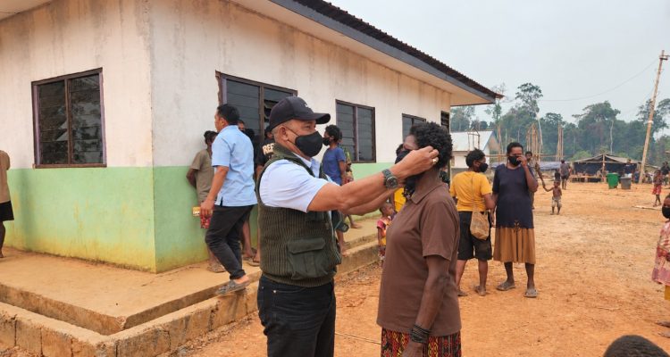Salah seorang warga sedang dikenakan masker di Kampung Asiki, Distrik Jair, Kabupaten Boven Digoel – Surya Papua/IST