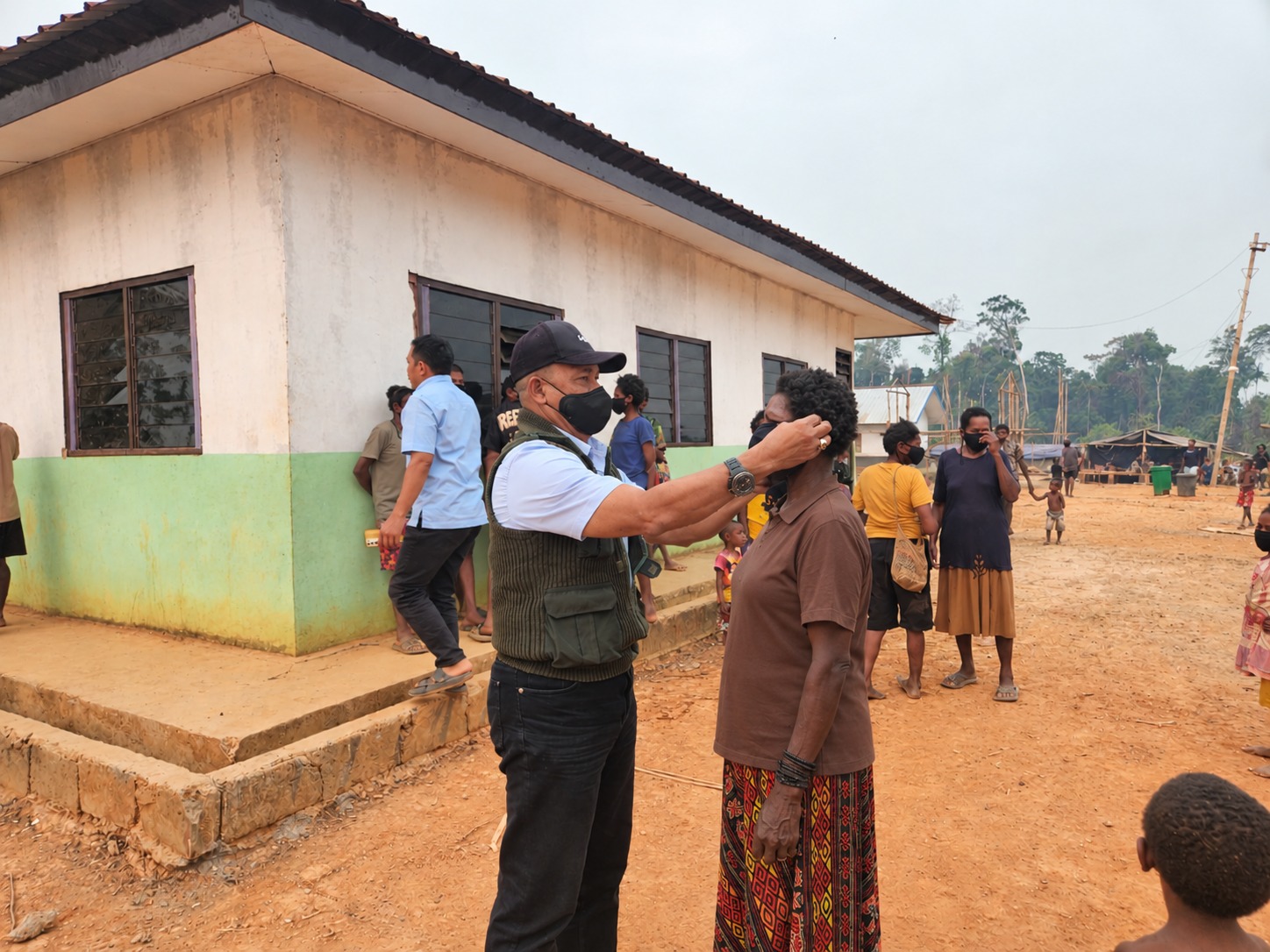 Salah seorang warga sedang dikenakan masker di Kampung Asiki, Distrik Jair, Kabupaten Boven Digoel – Surya Papua/IST